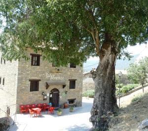 a building with red tables and chairs in front of a tree at Albergue Las Almunias in Las Almunias