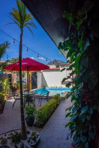 a patio with a palm tree and a red umbrella at El Delfin Hotel y Restaurante in San Pedro La Laguna