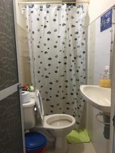 a bathroom with a shower curtain with a toilet and a sink at Hotel Princesa Katia in Necoclí