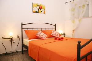 a bedroom with a bed with orange sheets and pillows at Apartments Bašić in Split