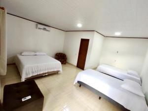 a bedroom with two beds and a table in it at Pousada Oliveiras in Caravelas
