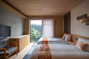 a hotel room with two beds and a large window at Hotel Legasta Kyoto Higashiyama Sanjo in Kyoto