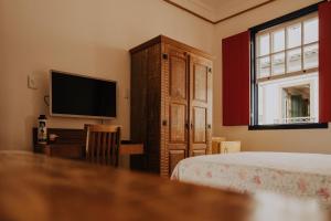 um quarto com uma cama e uma televisão de ecrã plano em Pousada Casa do Pilar em Ouro Preto
