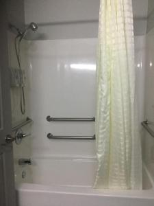 a bathroom with a tub and a shower curtain at Muskogee Inn and Suites in Muskogee