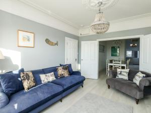 a living room with a blue couch and a table at Chesil Views in Portland