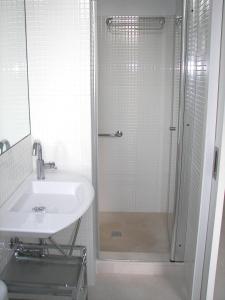 baño blanco con ducha y lavamanos en Villa Cel, en Cala en Blanes