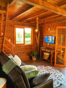 - un salon avec un canapé et un bureau dans une cabine dans l'établissement Chalé Recanto Verde dos Canyons, à Praia Grande