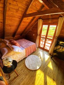 Cette chambre mansardée comprend un lit et une fenêtre. dans l'établissement Chalé Recanto Verde dos Canyons, à Praia Grande