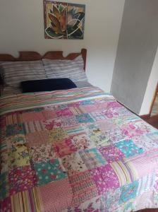 a bed with a colorful quilt on top of it at Casa Pereira Visconde de Mauá in Visconde De Maua
