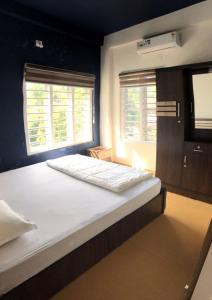 uma cama grande num quarto com duas janelas em Royal residency em Tindummal