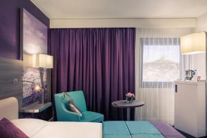 
a room with a bed, a chair, and a window at Mercure Marseille Centre Vieux Port in Marseille
