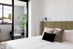ein Schlafzimmer mit einem weißen Bett und einem schwarzen Kissen in der Unterkunft Caroline Serviced Apartments Richmond in Melbourne