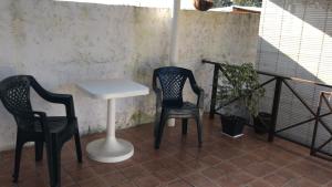 Duas cadeiras e uma mesa numa varanda em Confortable espacio en Minas em Minas