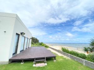 a house with a wooden deck next to the beach at ゴールデンマイルヴィラ in Amami