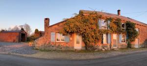 uma velha casa de tijolos com hera a crescer nela em Le Gîte au bord de la Forêt em Monthermé