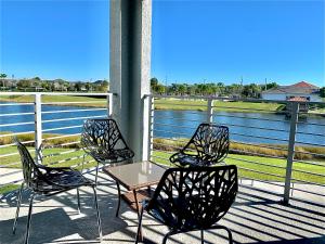 three chairs and a table on a porch with a view of the water at !3B2B! Beautiful Lake View! Baby Friendly! FREE WATER PARK! NO Resort Fee! 5 Miles to Disney! Storey Lake 3141 Room #201 in Kissimmee