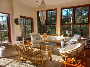 a living room with couches and chairs and windows at The Junglehouse Noosa in Doonan