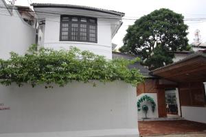 uma casa branca com uma parede branca e árvores em Lost & Found - Colombo em Colombo