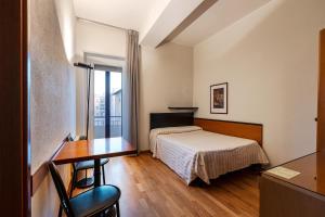 Una habitación de hotel con una cama, un escritorio y una mesa. en Hotel Nuova Grosseto, en Grosseto