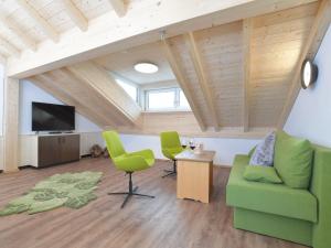 uma sala de estar com cadeiras verdes e uma televisão em Ferienhaus Birkenweg em Oberstdorf