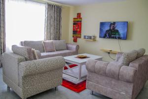 a living room with two chairs and a table at Lux Suites Milimani Luxe Apartments kisumu in Kisumu