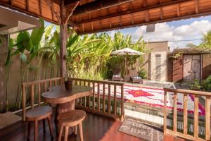 um pátio com uma mesa e bancos numa varanda em Sridewi Villas Ubud em Ubud