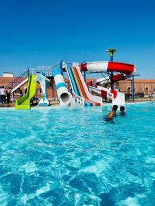 a person in a swimming pool next to a water slide at Hotel & Resort Golden Marina Yanbu in Yanbu