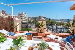 einen Balkon mit Tischen und Stühlen und Stadtblick in der Unterkunft Genteel Home Plaza de la Marina in Málaga