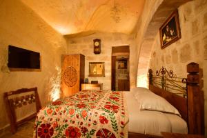 a bedroom with a bed with a floral bedspread at NOSTALJİ CAVE SUİT HOTEL in Nevşehir