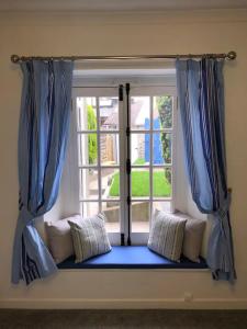 a window with blue curtains and pillows in front of it at The Retreat @ The Old Smithy, Colebrook Village in Plymouth