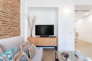 a living room with a television on a wooden stand at Genteel Home Julio César in Seville