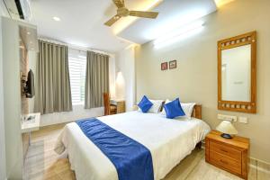 a bedroom with a bed with blue pillows and a mirror at Perumayan Arcade in Cochin