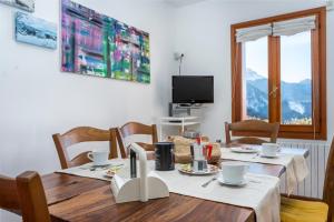 ein Esszimmer mit einem Tisch, Stühlen und einem TV in der Unterkunft Panoramic House Carnia - Mountain View APT with Parking and Terraces in Ligosullo
