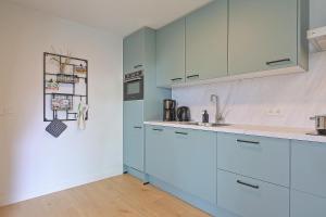 een keuken met blauwe kasten en een wastafel bij Vakantiehuis Poldertje 1A - Baddomburg in Domburg