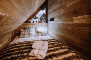 Ce lit se trouve dans une chambre en bois dotée de serviettes. dans l'établissement Diament Apartamenty Mozaika w Centrum z balkonem, à Zakopane