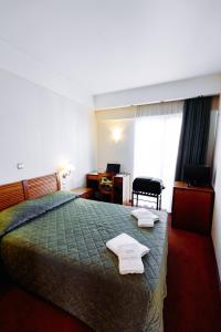 Una habitación de hotel con una cama con dos toallas. en Athens Mirabello, en Atenas