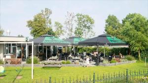 a patio with tables and umbrellas in a yard at 't zeeuwse achteruusje in Sint Annaland