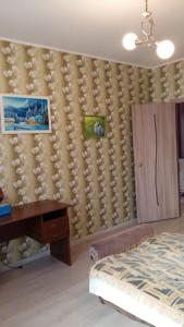 a bedroom with a bed and a desk and a wall at Квартира у моря in Odesa