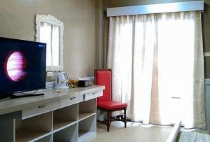 Habitación con escritorio, TV y silla roja. en RedDoorz @ Vine Molave, en Molave