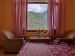 Schlafzimmer mit einem Bett und einem Fenster mit rosa Vorhängen in der Unterkunft HOTEL MOUNTAIN VIEW in Jyotirmath