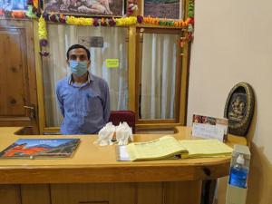 Ein Mann, der hinter einem Schreibtisch steht und eine Maske trägt. in der Unterkunft HOTEL MOUNTAIN VIEW in Jyotirmath