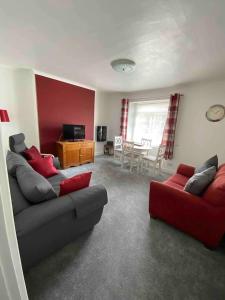 a living room with a couch and a red chair at The Retreat @ The Old Smithy, Colebrook Village in Plymouth