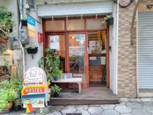 uma porta da frente de uma loja com um banco no exterior em Guest House mii em Osaka