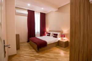 a bedroom with a bed and a window with red curtains at City Apartments in Baku