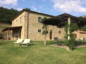 a stone building with tables and chairs in a yard at Locanda del Viandante - Valle Apartments & Pool in Anghiari