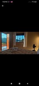 a bedroom with a bed and a window with a view at Chalé Mirante Das Serras Ibicoara-BA in Ibicoara