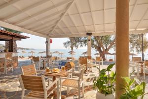 un restaurante con mesa y sillas en la playa en Princess Tia Hotel en Samos