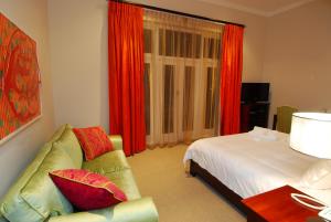 a bedroom with a bed and a couch and a window at Wild Mushroom Country House in Stellenbosch