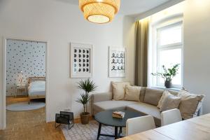 Large Apartments - Great for Groups - with Balcony or Terrace في فيينا: غرفة معيشة مع أريكة وطاولة