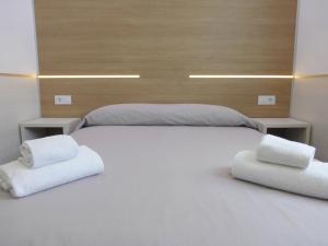 a large white bed with two white towels on it at Rentalmar Navarra family suites in Salou